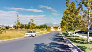 View of asphalt street featuring curbs, a residential view, a mountain view, and sidewalks