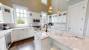 Kitchen featuring decorative backsplash, pendant lighting, white cabinetry, dark wood-type flooring, and glass insert cabinets