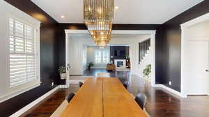 Dining space with dark wood-style floors, recessed lighting, and stairs