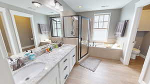 Full bathroom featuring a garden tub, double vanity, a stall shower, and light wood-style flooring