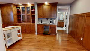 Kitchen with brown cabinetry, wine cooler, light wood finished floors, open shelves, and recessed lighting