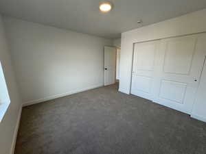 Unfurnished bedroom featuring dark colored carpet and a closet