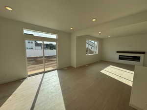 Unfurnished living room with recessed lighting, a glass covered fireplace, and light wood-style flooring