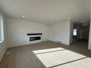 Unfurnished living room with a fireplace, recessed lighting, and light wood-style floors