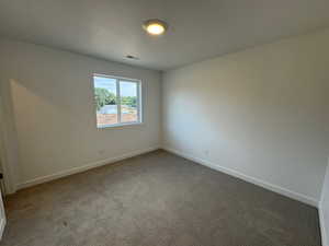 Carpeted empty room featuring baseboards and a textured ceiling