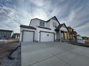 View of front of home with stucco siding, concrete driveway, and a garage