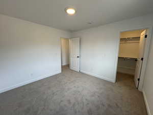 Unfurnished bedroom with carpet floors and a spacious closet