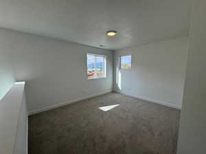 Carpeted empty room with a textured ceiling and baseboards