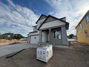 View of front facade featuring driveway, stucco siding, and an attached garage