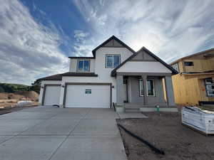 View of front facade with stucco siding, driveway, a garage, and covered porch