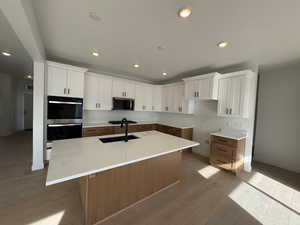Kitchen with white cabinetry, recessed lighting, light wood-style flooring, an island with sink, and appliances with stainless steel finishes