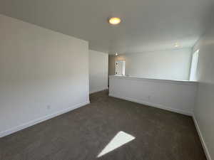 Spare room featuring dark carpet and baseboards