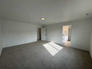 Unfurnished bedroom featuring light carpet and connected bathroom
