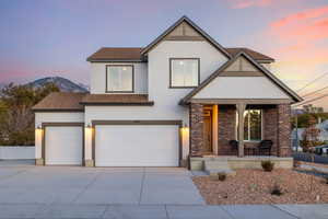 View of front of property featuring a shingled roof, concrete driveway, stucco siding, brick siding, and a garage