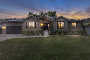 Ranch-style home featuring an attached garage, a front yard, roof mounted solar panels, and brick siding