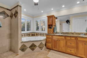 Bathroom with ornamental molding, a garden tub, double vanity, recessed lighting, and a ceiling fan