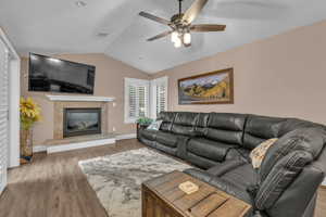 Living area featuring vaulted ceiling, light wood-type flooring, a high end fireplace, and ceiling fan