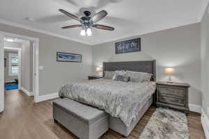 Bedroom featuring ornamental molding, wood finished floors, ceiling fan, and baseboard heating