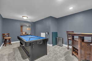 Recreation room featuring light carpet, a textured ceiling, and billiards