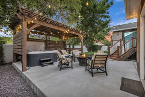 Fenced backyard featuring a patio, a fire pit, a hot tub, and a pergola