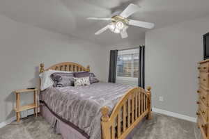 Bedroom with light carpet, ceiling fan, and a textured ceiling