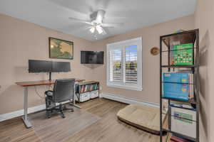 Home office featuring light wood finished floors, a baseboard radiator, and a ceiling fan
