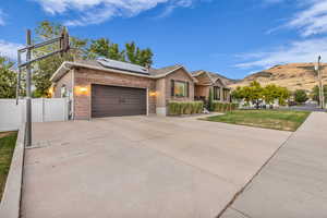 View of front of house featuring solar panels, brick siding, an attached garage, driveway, and a mountain view