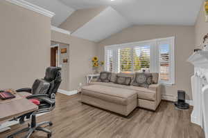 Office space featuring light wood finished floors, lofted ceiling, and baseboard heating