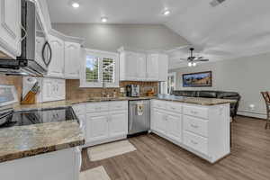 Kitchen with dark stone counters, white cabinetry, tasteful backsplash, lofted ceiling, and recessed lighting