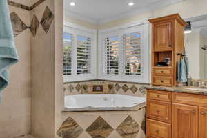 Full bathroom featuring vanity, a garden tub, and crown molding