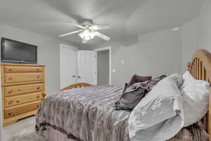 Bedroom with light carpet, a textured ceiling, and ceiling fan