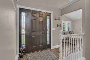 Foyer entrance featuring wood finished floors, a baseboard radiator, and lofted ceiling
