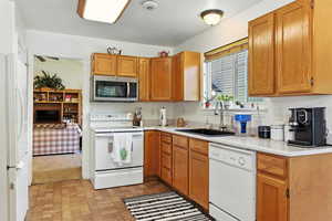 Kitchen with white appliances, light countertops, and brown cabinets