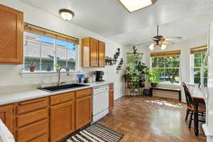 Kitchen featuring light countertops, brown cabinets, white appliances, brick patterned floors, and a ceiling fan