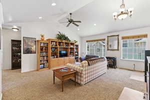 Living room featuring light colored carpet, ceiling fan, a wood stove, high vaulted ceiling, and a chandelier—tons of natural light from large Garden Windows.
