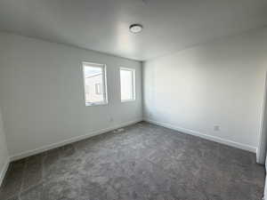 Carpeted spare room featuring baseboards