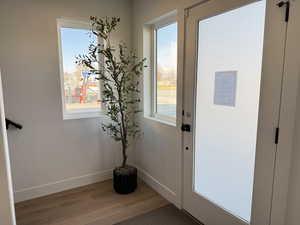 Doorway to outside with baseboards and wood finished floors