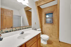 Full bathroom featuring wood walls, vanity, and light wood-style floors