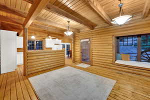 Reception area with log walls, a ceiling fan, and a wooden ceiling with exposed beams