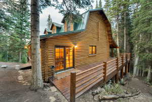 View of side of property featuring log exterior, a deck, a gambrel roof, and a metal roof