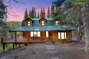 Log home with covered porch, a metal roof, and log exterior