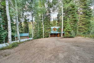 View of front of property featuring a porch, a wooded view, and a metal roof