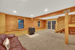 Living area with stairs, a wood stove, beamed ceiling, rustic walls, and recessed lighting