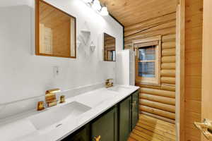Full bathroom with log walls, double vanity, light wood finished floors, and wood ceiling