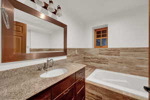 Bathroom with a bath, vanity, and tile walls