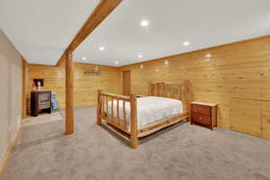 Bedroom with recessed lighting, carpet floors, wood walls, and beam ceiling