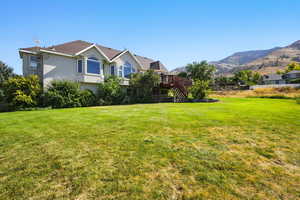 View of green lawn with a deck with mountain view and stairs