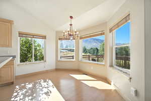 Unfurnished dining area with lofted ceiling, a chandelier, a mountain view, and light wood-style floors