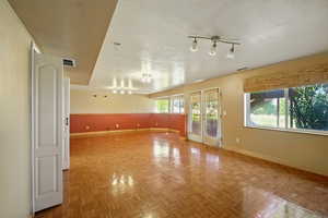 Spare room featuring a textured ceiling, french doors, and track lighting