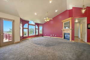 Unfurnished living room featuring light colored carpet, a glass covered fireplace, high vaulted ceiling, ceiling fan, and recessed lighting